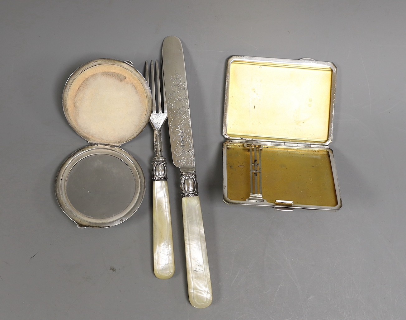 Two Art Deco silver and two colour enamel compacts, largest 85mm and a Victorian mother of pearl handled silver christening knife and fork.